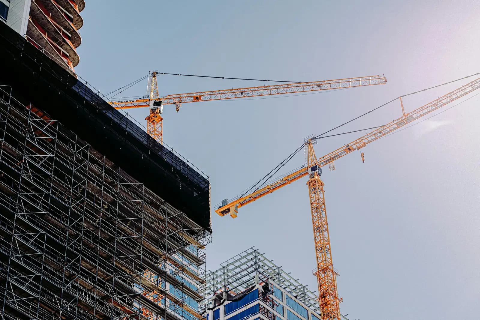 A building under construction with tower cranes overhead
